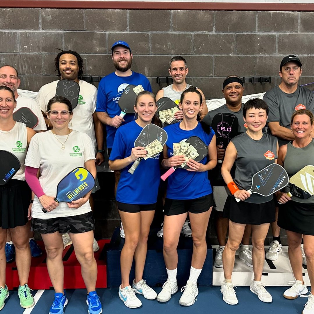 dynamic pickleball match action shot with players competing on outdoor court, teams wearing matching jerseys, intense rally moment, professional sports photography